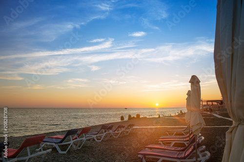 Beautiful sunset on the sea. Sunbeds on the beach.
