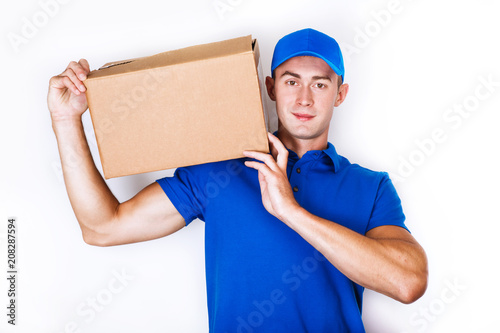 Cheerful delivery man. Happy young courier holding a cardboard box and smiling