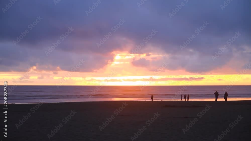 People walk along the beach during magical sunset People walk along the beach during magical sunset