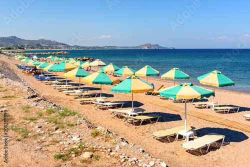 Sun loungers with umbrellas on sandy Kolymbia beach in sunny day. Rhodes island, Greece