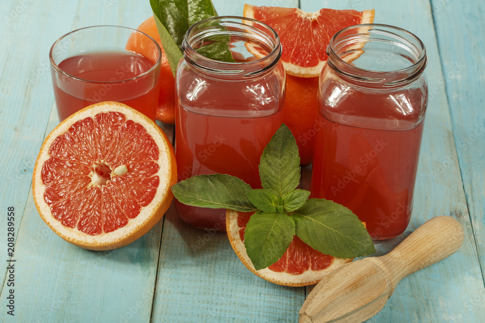 Fototapeta Grapefruit juice and fresh grapefruit on a wooden background. Fresh grapefruit juice in a glass bowl, copy space.