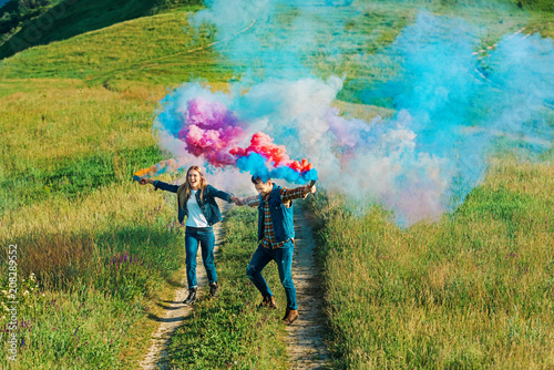 high angle view of couple holding colorful smoke bombs on rural meadow