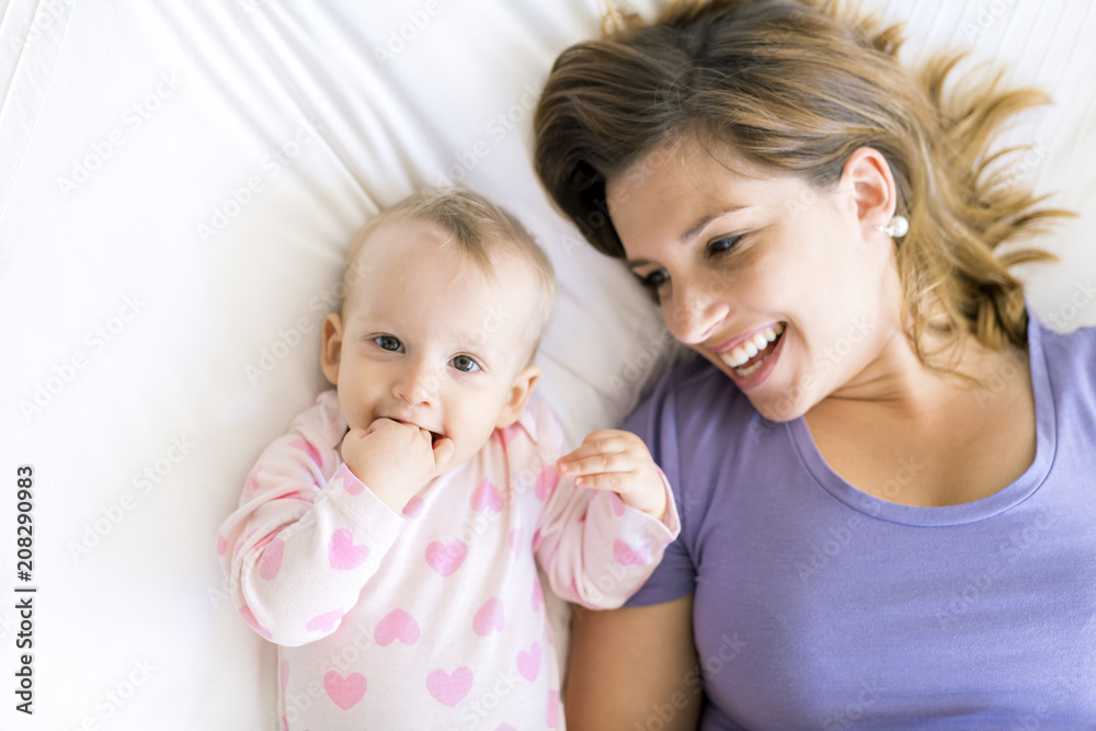Happy mother with baby lying on bed at home Happy mother with baby lying on bed at home