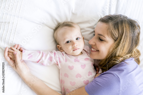 Happy mother with baby lying on bed at home photo