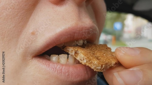 young woman with glasses sitting in the car and eating organic cookies. healthy diet, lips close up
