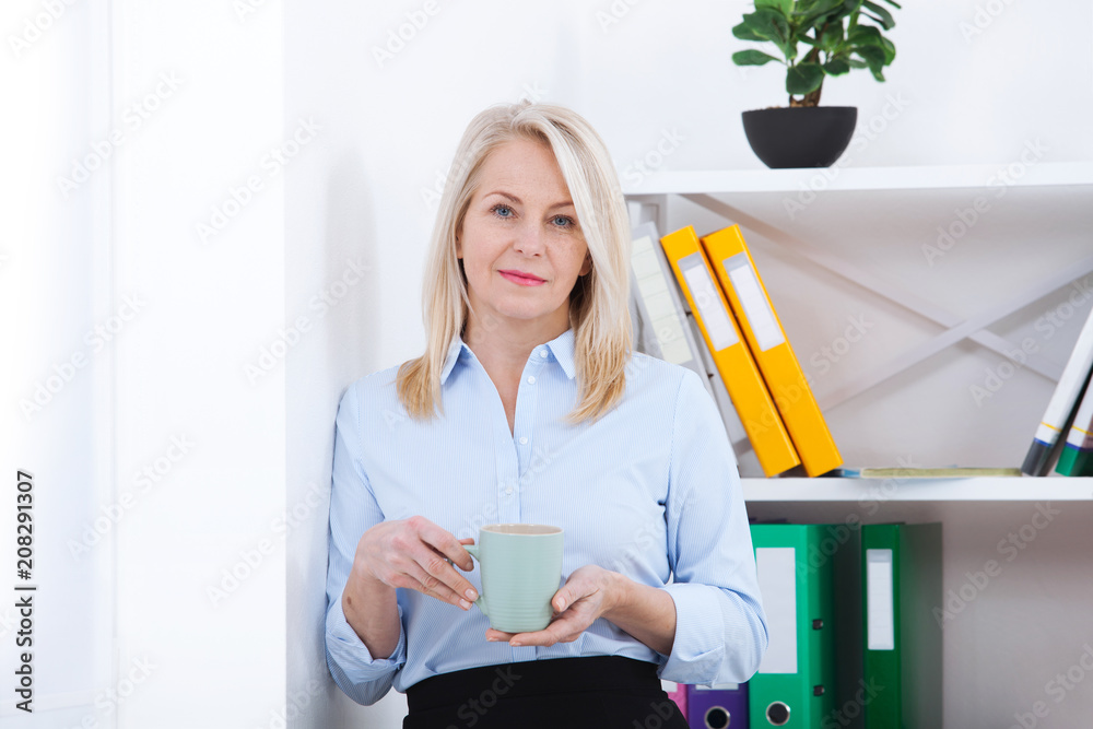 Smiling middle aged businessman with a cup of coffee in the office. Coffee break. Smiling middle aged businessman with a cup of coffee in the office. Coffee break.