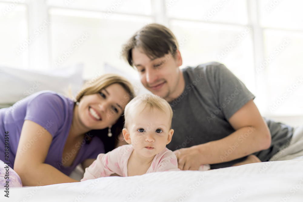 Portrait of beautiful young parents and cute baby on bed