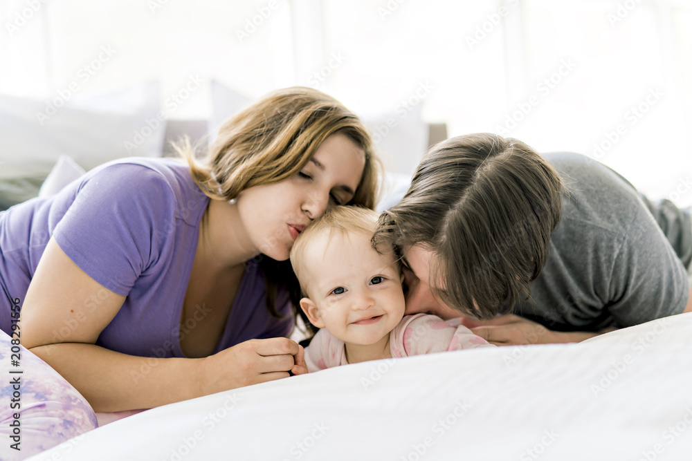 Portrait of beautiful young parents and cute baby on bed Portrait of beautiful young parents and cute baby on bed