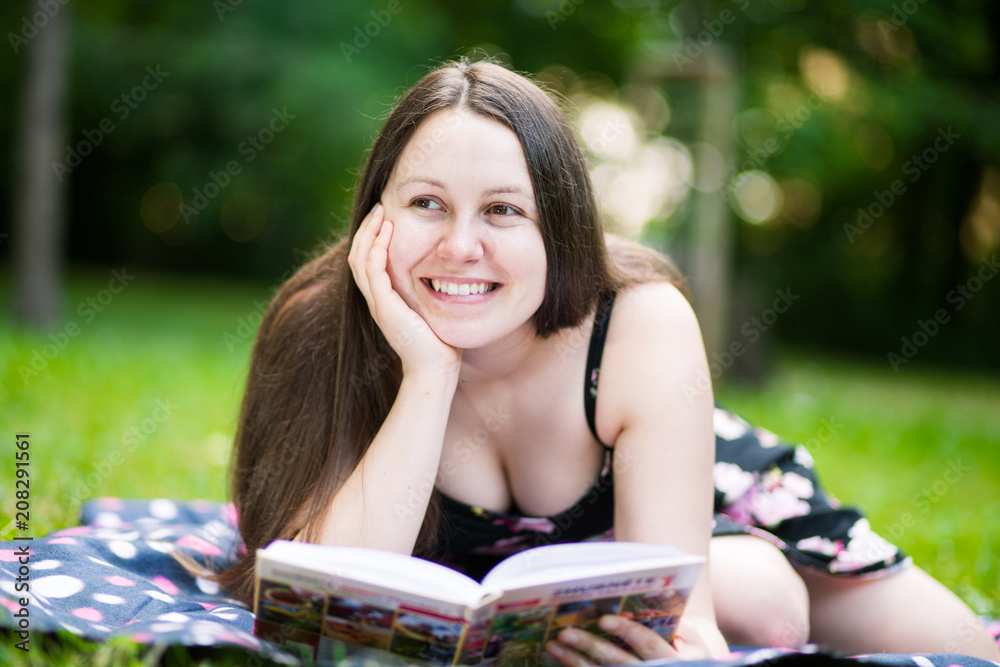 Portrait of young brunette woman reading a book in outside, park Portrait of young brunette woman reading a book in outside, park