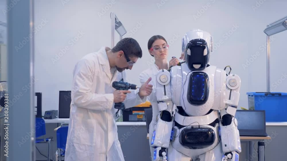 Workers fix a robot. Workers fix a robot.