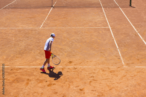The boy plays tennis on the orange dirt court. Court hard © Rak