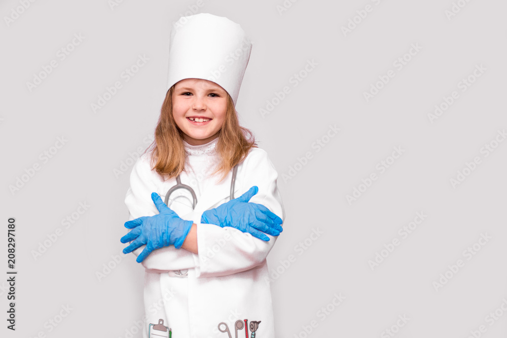 Smiling little girl in medical uniform and blue gloves looking at camera isolated on white Smiling little girl in medical uniform and blue gloves looking at camera isolated on white