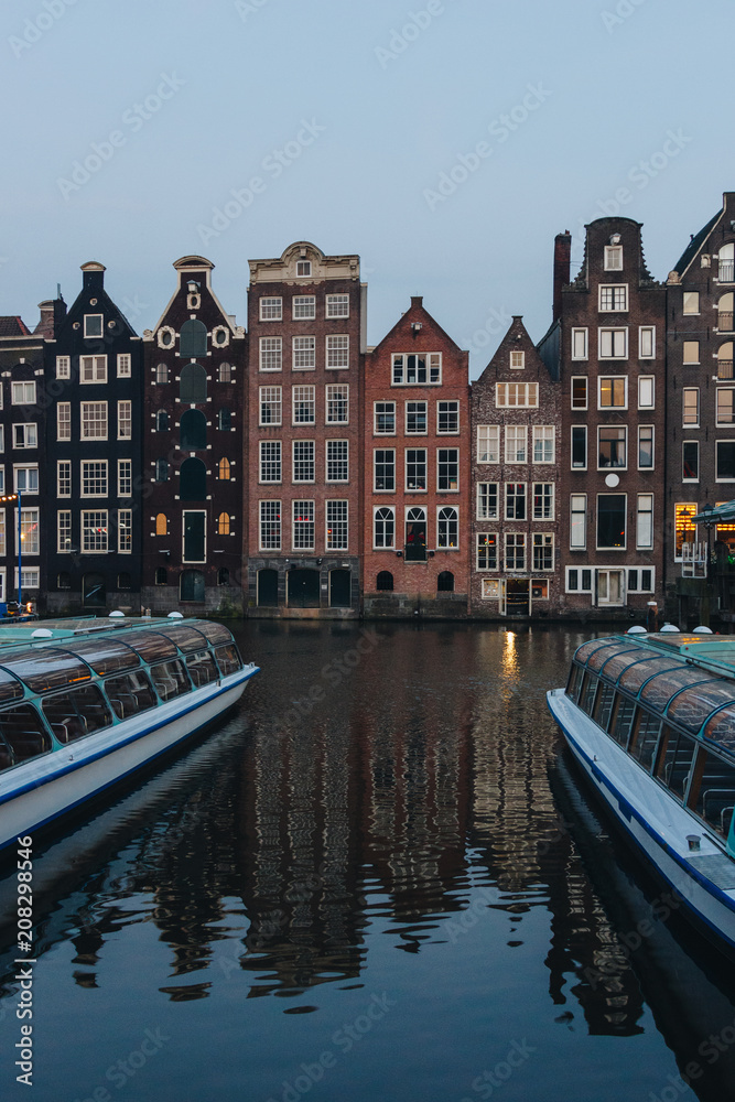20 MAY 2018 - AMSTERDAM, NETHERLANDS: facades of ancient building above canal on twilight, Amsterdam, Netherlands