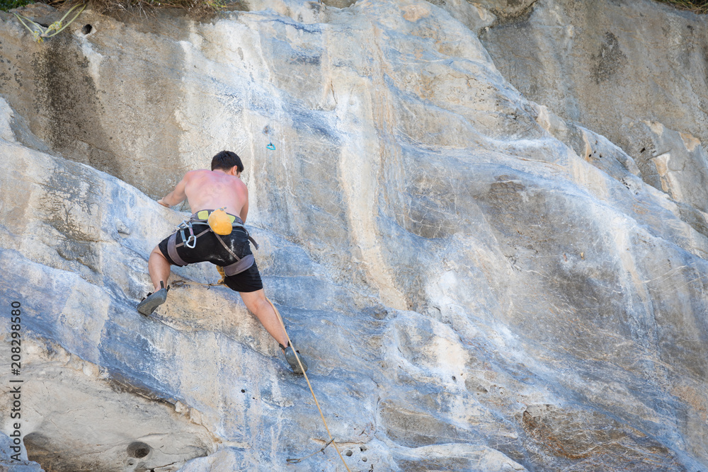 Young man rock climbing on white mountain