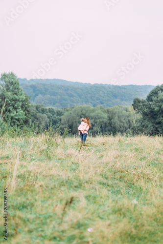 Mother and little daughter playing together in a park. Happy cheerful family. Mother and baby kissing, laughing and hugging in nature outdoors © sofiko14