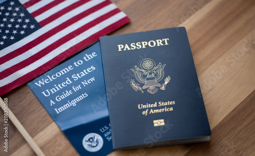 Passport of USA (United states of America) next to a Guide for new Immigrants - Welcome to the United states and American Flag. Wooden Background. photo