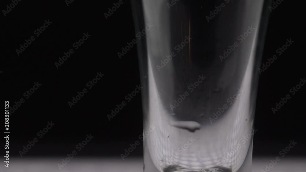 Pour alcohol into the glass. A glass of vodka on the table. The sweating glass of vodka. Slow motion is poured into a glass of vodka. Close-up of alcohol is poured into a glass. Pour alcohol into the glass. A glass of vodka on the table. The sweating glass of vodka. Slow motion is poured into a glass of vodka. Close-up of alcohol is poured into a glass.