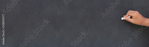 Main d'enfant écrivant à la craie sur un tableau noir à l