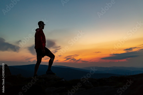 Fototapeta Naklejka Na Ścianę i Meble -  Man celebrating sunset looking at view in mountains
