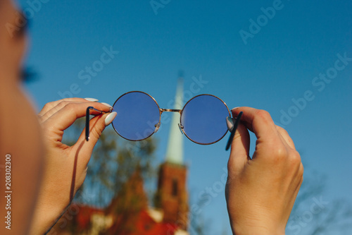 cropped shot of woman holding stylish sunglasses and looking through