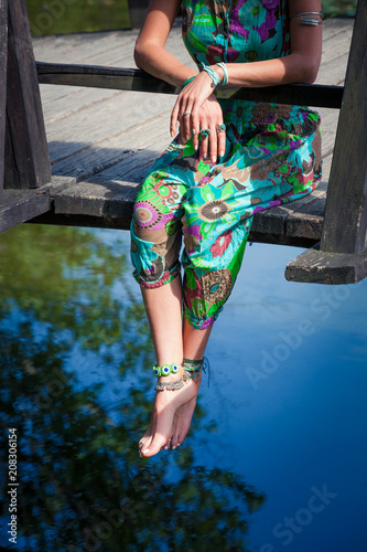 young woman sit on wooden bridge over the pond relaxing barefoot boho style clothes and fashion details