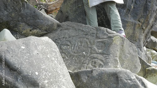 Female hiker goes past petroglyph not noticing the ancient carvings photo