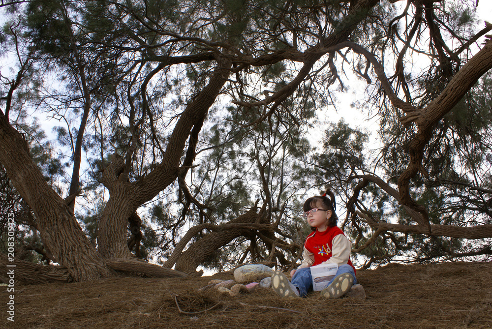 Little girl sitting under a tree Little girl sitting under a tree