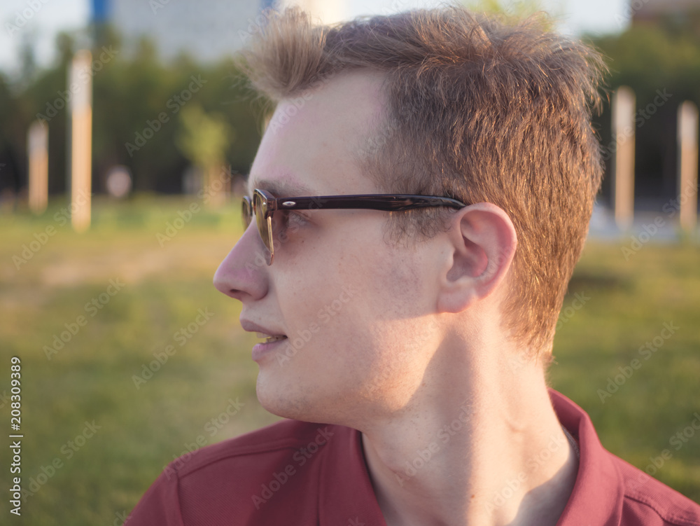 young man portrait in fashionable sunglasses walking in the park young man portrait in fashionable sunglasses walking in the park