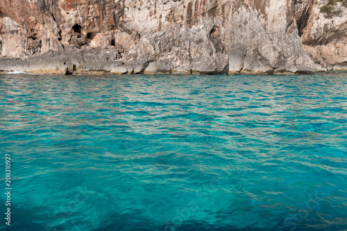 Turquoise colored water in front of coastal cliff