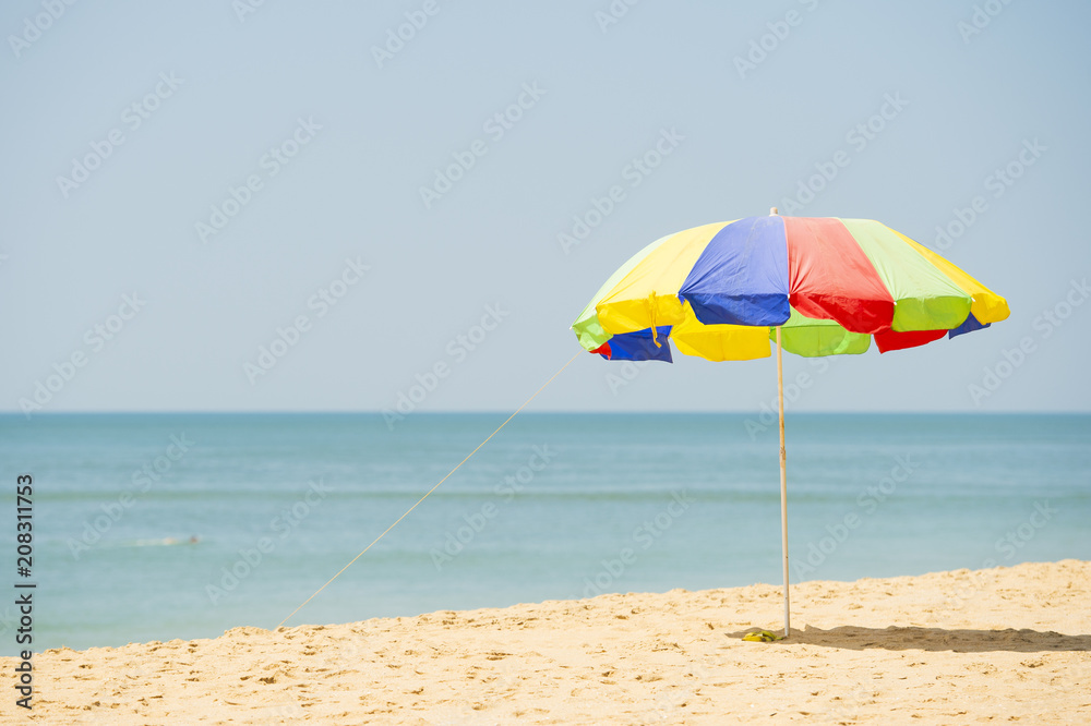 A colorful umbrella is open on a tropical beach during a sunny day. A colorful umbrella is open on a tropical beach during a sunny day.