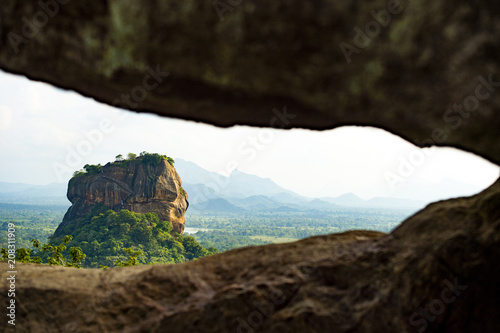 Spectacular view of the Lion rock framed by a rock surrounded by green and rich vegetation. Picture, taken from Pidurangala Rock in Sigiriya, Sri Lanka.