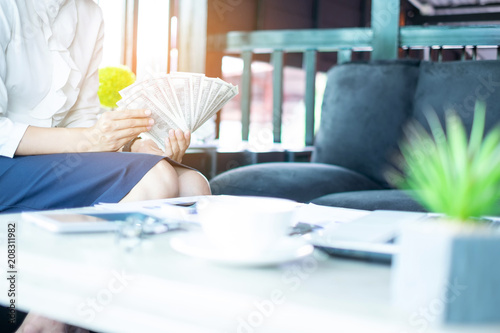 Businesswoman displaying a spread of cash at workplace