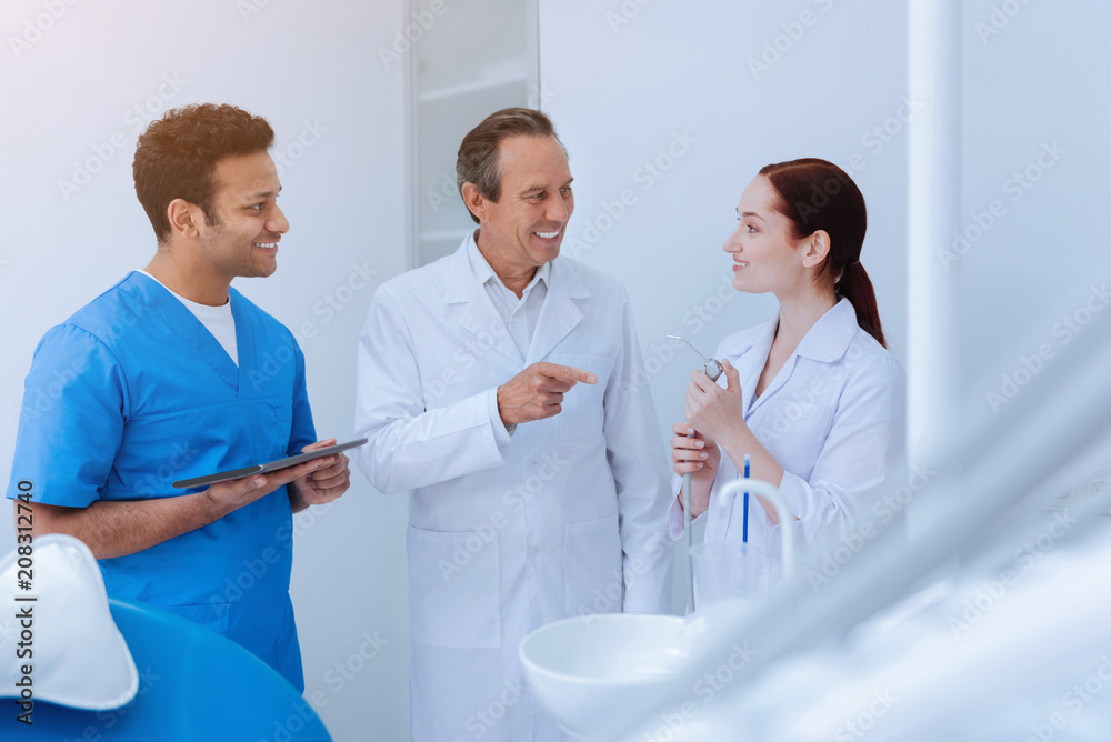 Fototapeta premium Your term. Attentive brunette male person wearing blue uniform standing in semi position while keeping his gadget in right hand