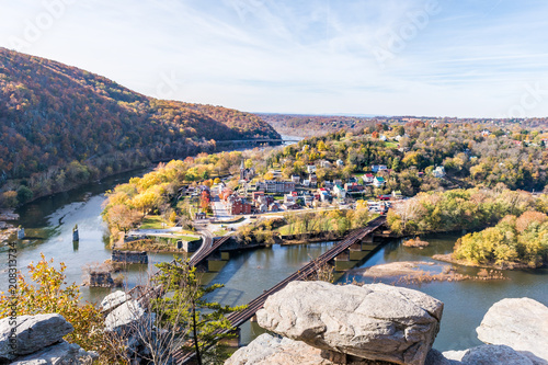 Harper's Ferry overlook closeup of cityscape with cliffs rocks, colorful orange yellow foliage fall autumn forest with small village town by river in West Virginia, WV photo