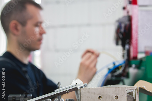 Electrician in overalls is working with energy panel and machinery equipment on plant photo