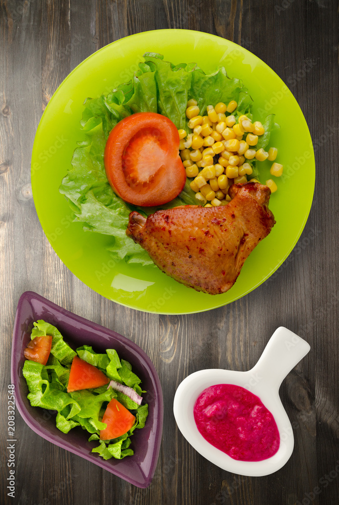 Plakat chicken wing with salad, corn and tomato on a plate