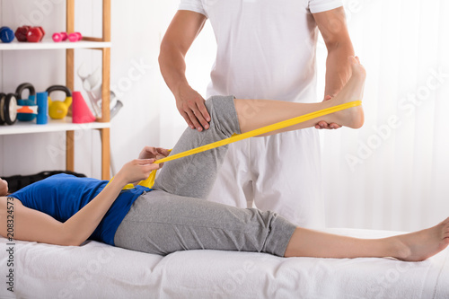 Physiotherapist Giving Leg Treatment With Exercise Band