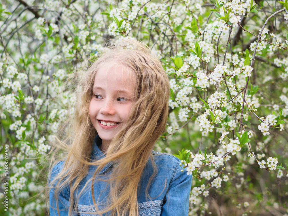 Portrait of a beautiful girl in a denim shirt next to a cherry tree. Portrait of laughing happy girl. Portrait of a beautiful girl in a denim shirt next to a cherry tree. Portrait of laughing happy girl.