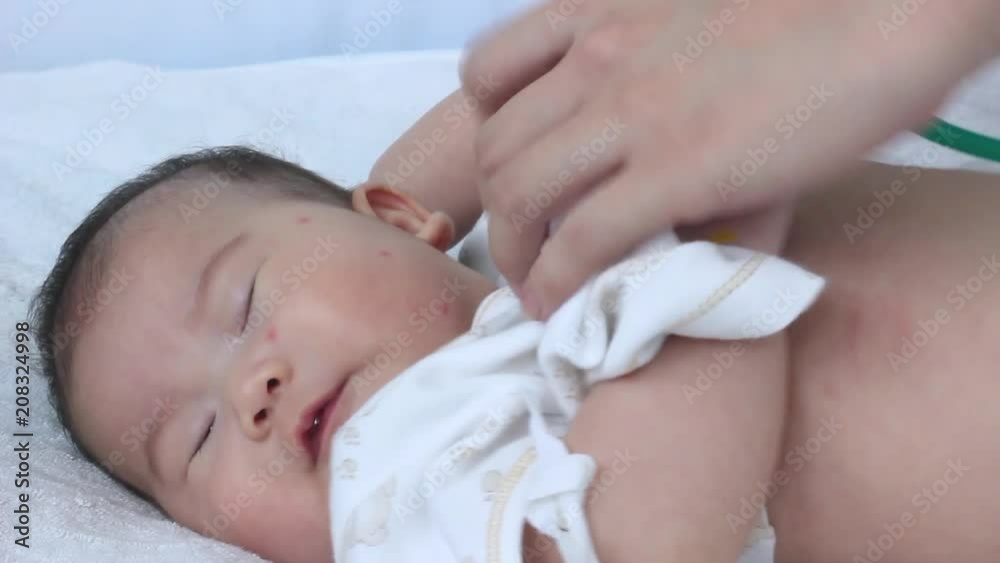 Pediatrician examining infant. Two months baby asian girl lying on sickbed in hospital. Pediatrician examining infant. Two months baby asian girl lying on sickbed in hospital.