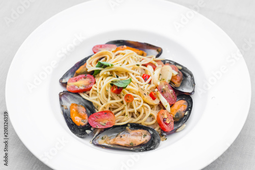 Pasta spaghetti with mussel and tomatoes isolated on white plate