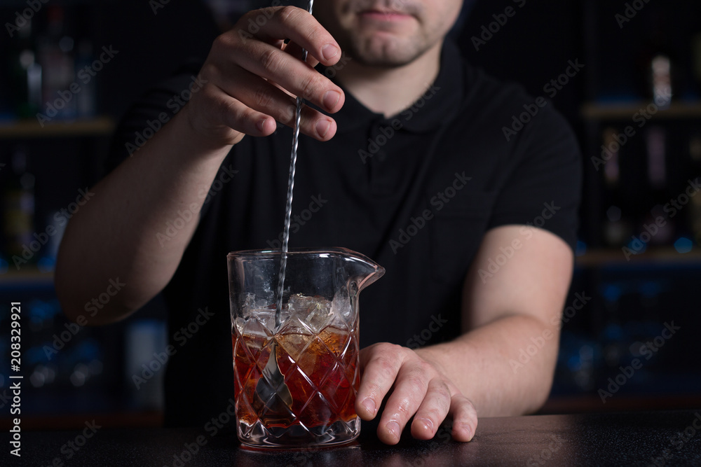 Bartender stirring alcoholic cocktail in a measuring glass Bartender stirring alcoholic cocktail in a measuring glass