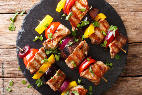Freshly prepared pork skewers with vegetables close-up on a slate plate. horizontal top view from above