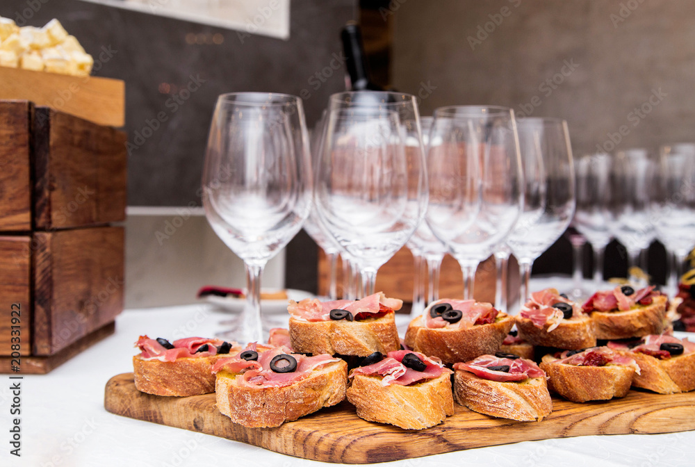 Snacks with ham on the banquet table and glasses of wine