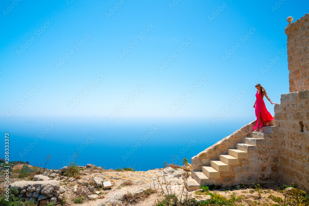 Φωτογραφία Beautiful girl in a long pink dress standing on the edge of the white cliffs by