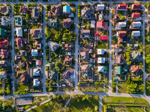 Aerial photography of a a cottage village with colorful houses, a good road, green trees and yards. Helicopter drone shot