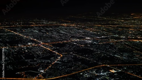 Illuminated city in dark night ,   aerial window seat view  airplane. Lights on approach to landing at airport photo