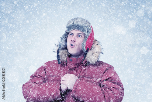 Frozen man in red winter clothes lets the steam out of his mouth, cold, snow, blizzard 