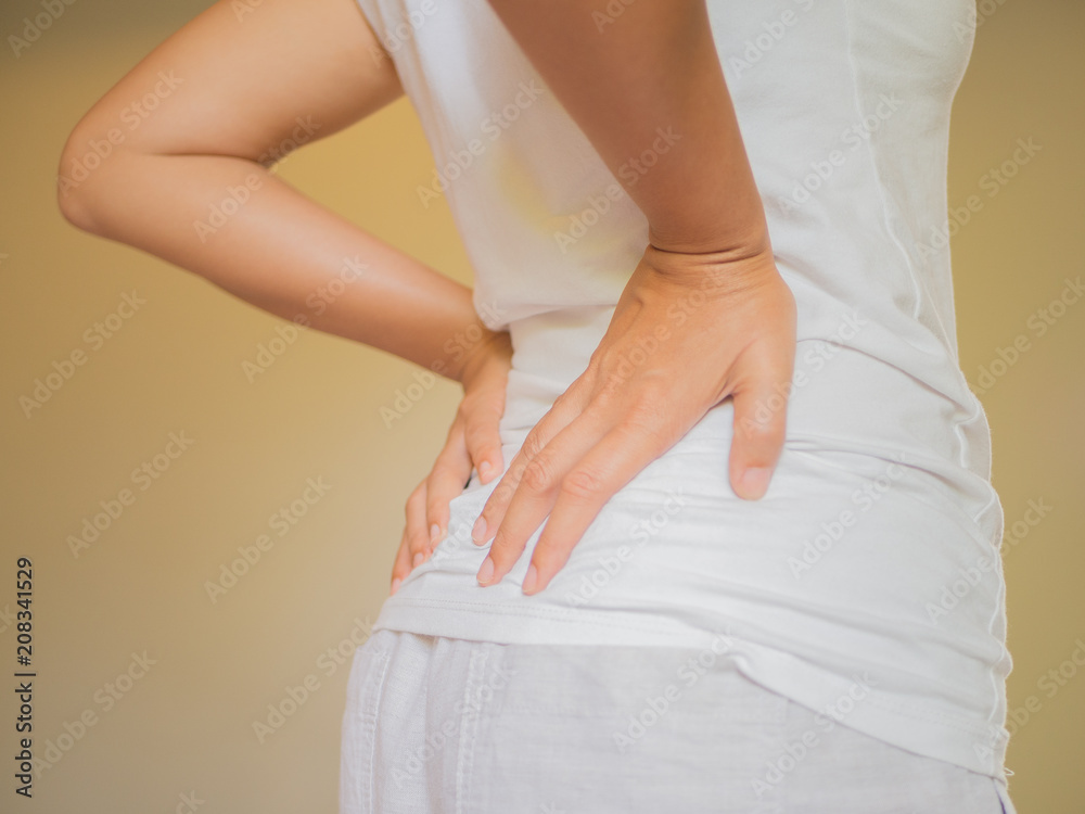 Young woman feeling pain in her back on the bed at home. Healthcare and medical concept.