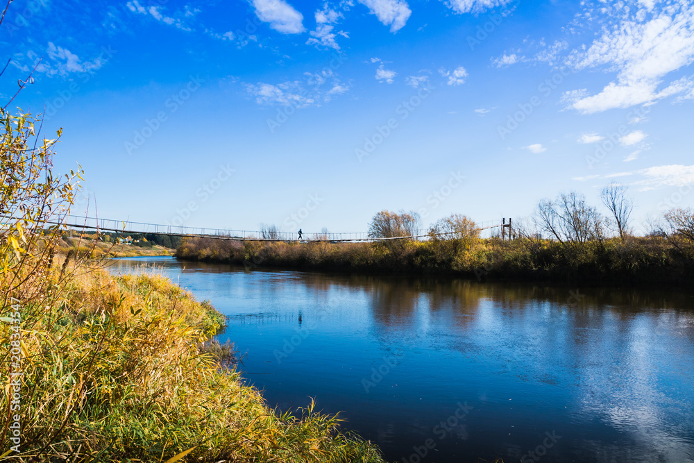 Fototapeta premium Bridge over the river and the autumn nature around