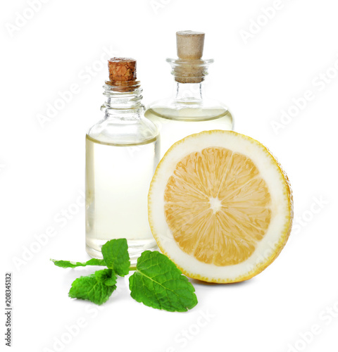 Bottles of citrus essential oil and lemon on white background